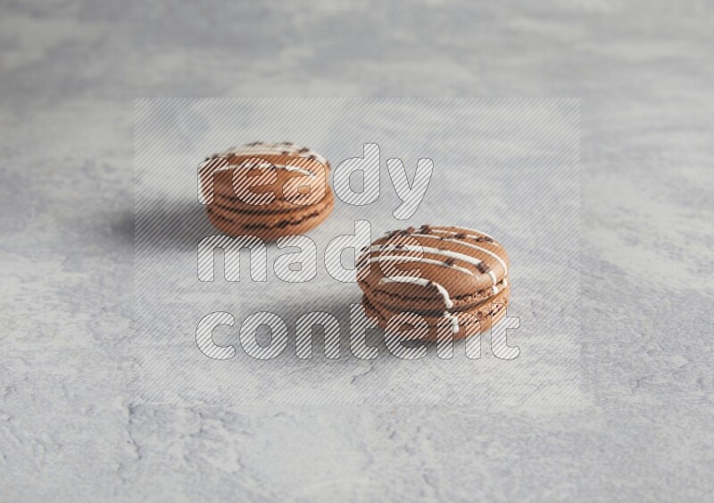 45º Shot of two Brown white marbleChocolate Caramel macarons  on white  marble background