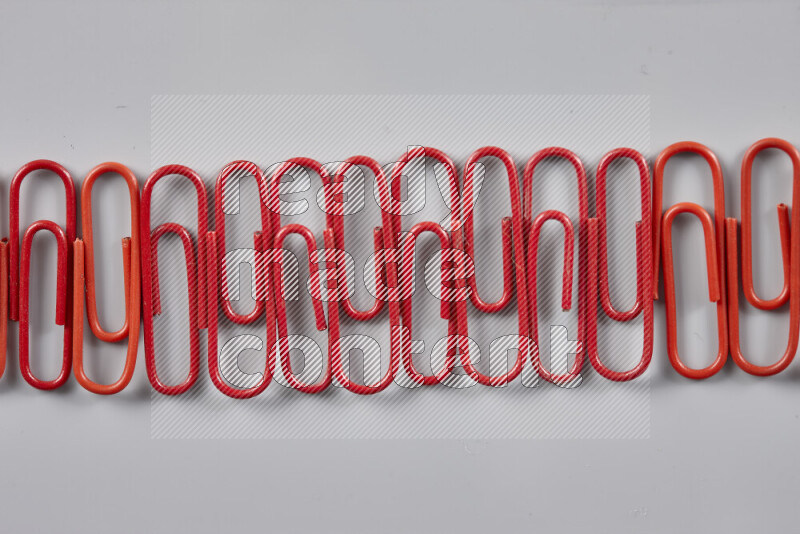 Red paper clips isolated on a grey background