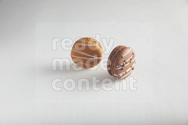 45º Shot of of two assorted Brown Irish Cream, and Brown white Chocolate Caramel macarons on white background