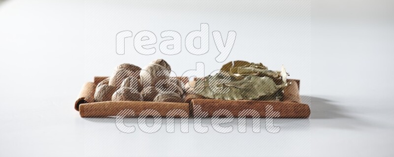 2 squares of cinnamon sticks full of bay laurel leaves and nutmegs on white flooring