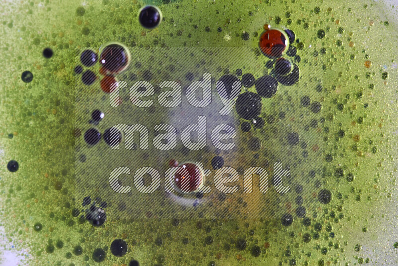 لقطات مقربة لقطرات ألوان مائية حمراء وخضراء وزرقاء على سطح الزيت على خلفية خضراء