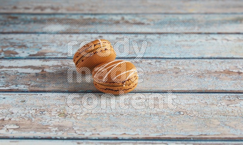 45º Shot of two Brown Irish Cream macarons on a  light blue wooden background