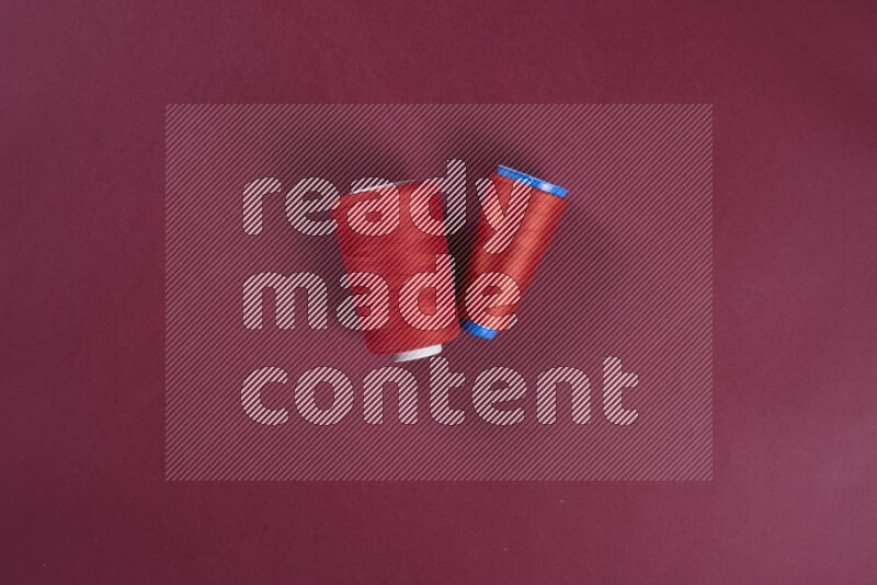 A red collection of sewing and tailoring tools arranged on a red background