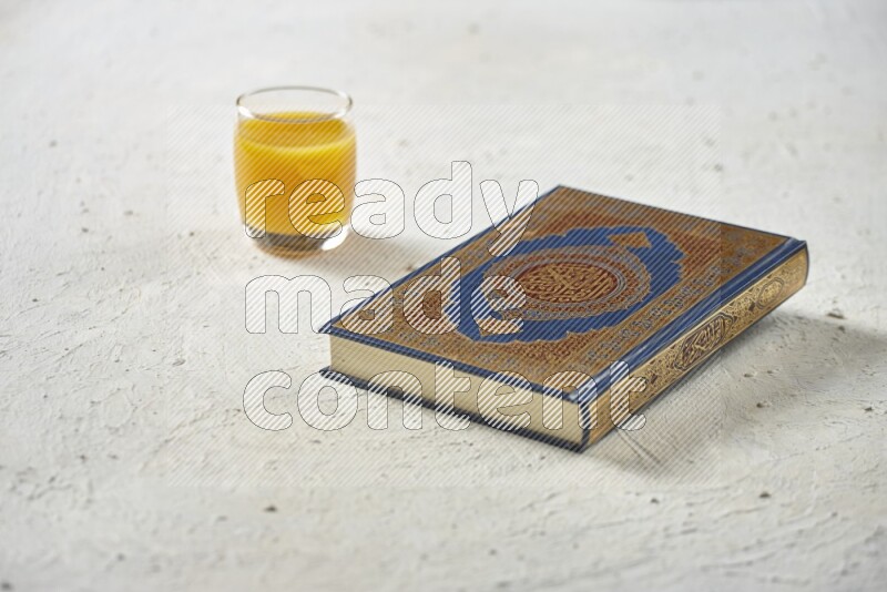 Quran with dates, prayer beads and different drinks all placed on textured white background