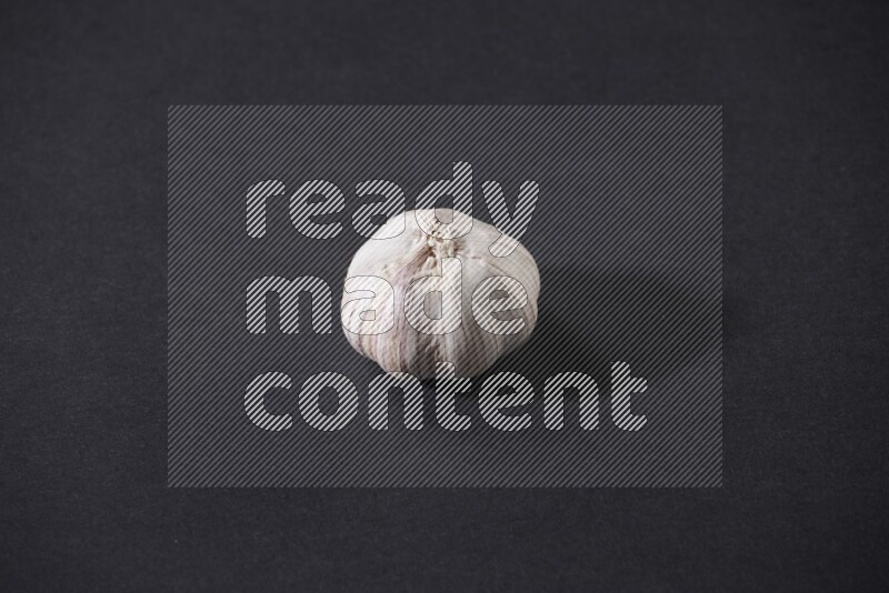 A whole garlic bulb placed on a black flooring
