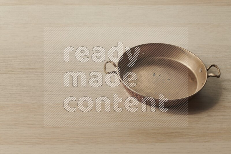 A small copper pan on light wooden background