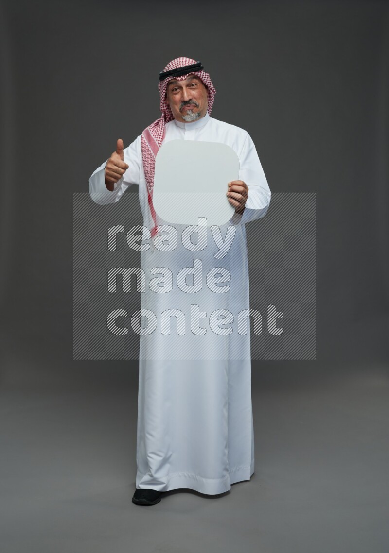 Saudi man with shomag Standing holding social media sing on gray background
