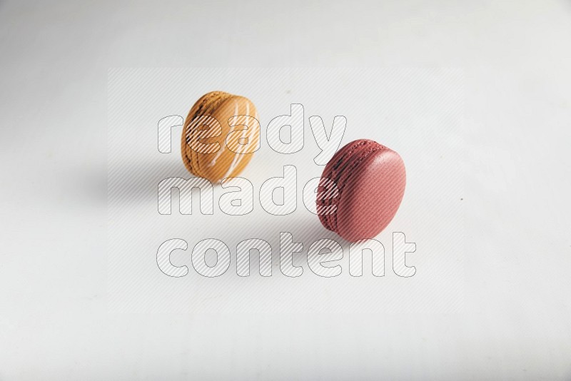 45º Shot of of two assorted Brown Irish Cream, and Red Velvet macarons on white background