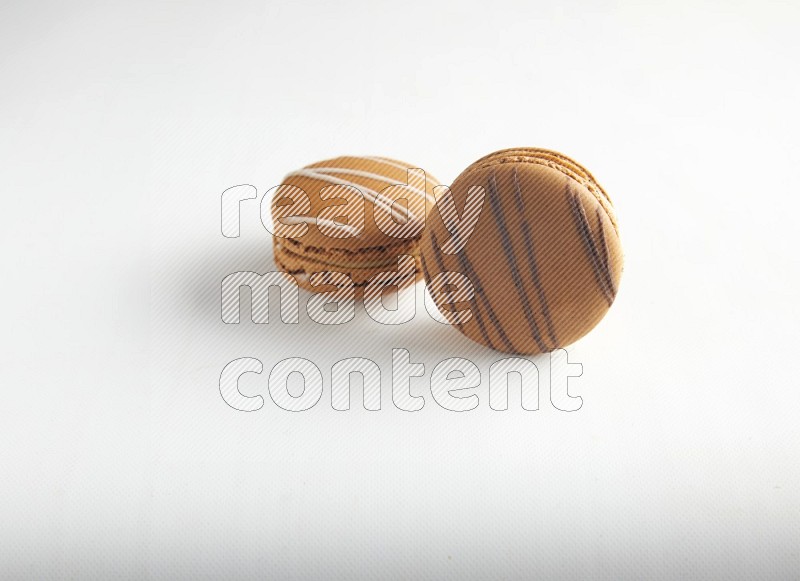 45º Shot of of two assorted Brown Irish Cream, and light brown  Almond Cream macarons on white background