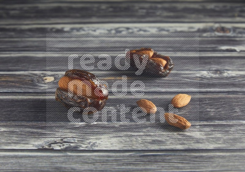 two almond stuffed madjoul dates on a wooden grey background