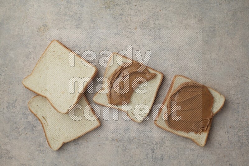 Creamy peanut butter on white toast and white toast slices on a light blue textured background
