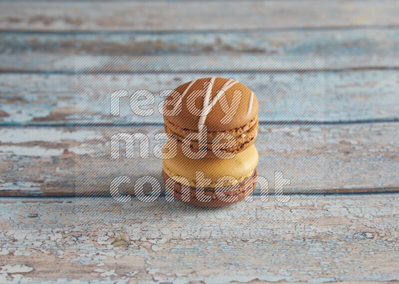 45º Shot of of two assorted Brown Irish Cream, and Yellow, and Brown Chai Latte macarons  on light blue background