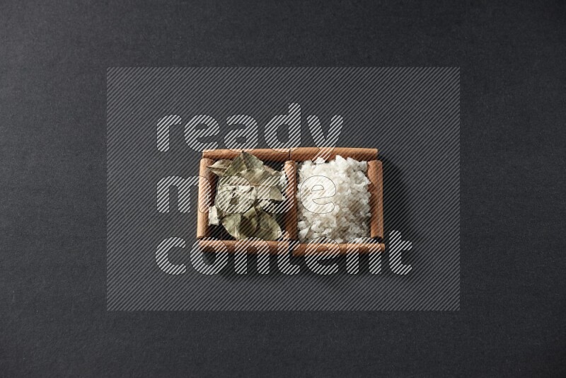 2 squares of cinnamon sticks full of salt and bay laurel on black flooring