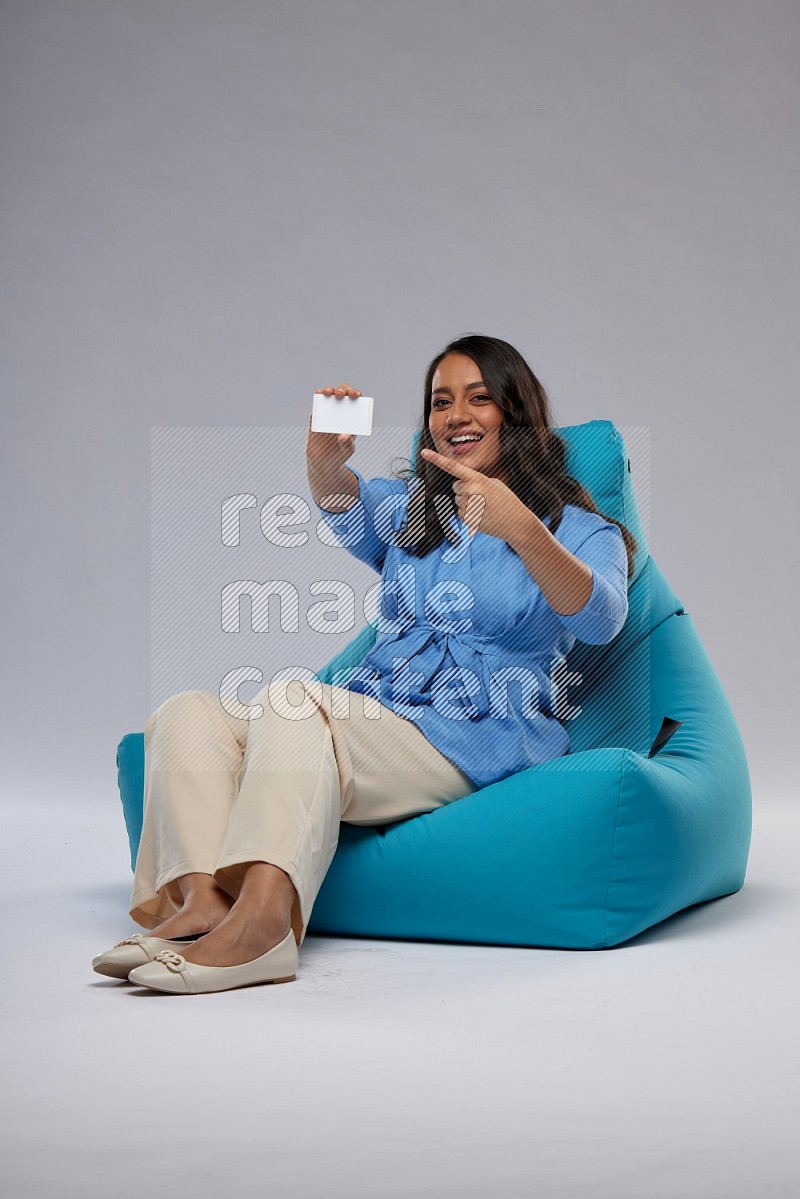 A woman sitting on a blue beanbag and holding ATM card