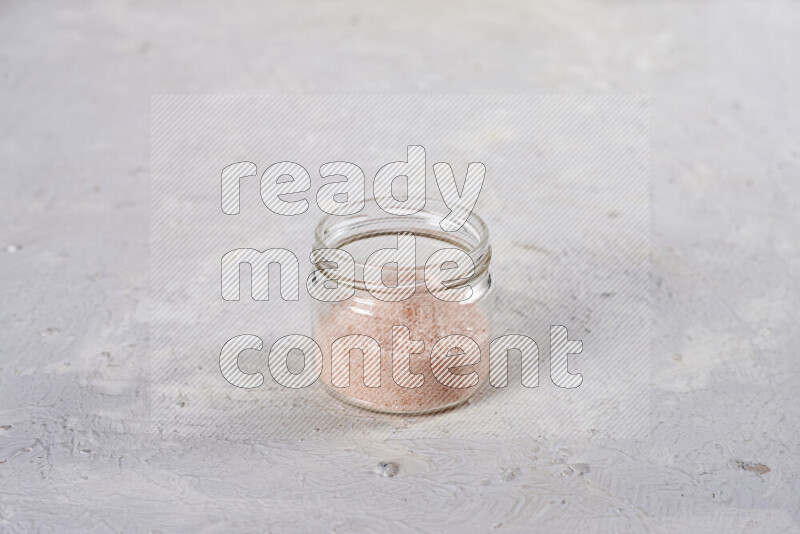 A glass jar full of fine himalayan salt on white background