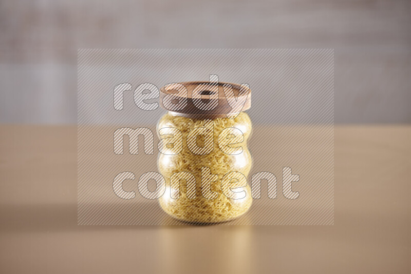 Raw pasta in glass jars on beige background