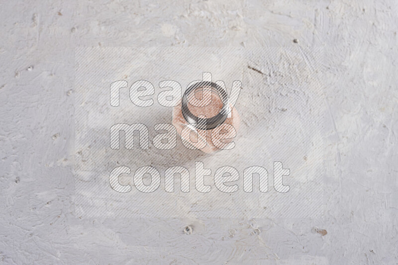 A glass jar full of fine himalayan salt on white background