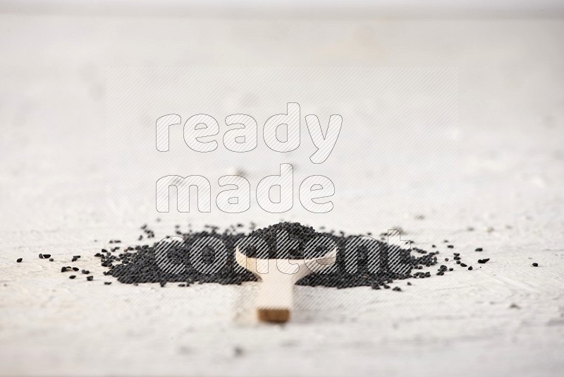 A wooden spoon full of black seeds on textured white flooring in different angles