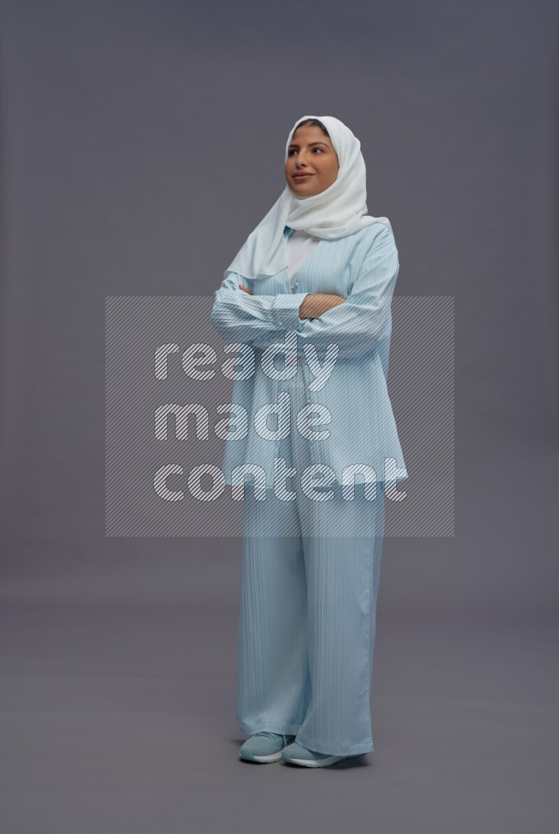 Saudi woman wearing hijab clothes standing with crossed arms on gray background