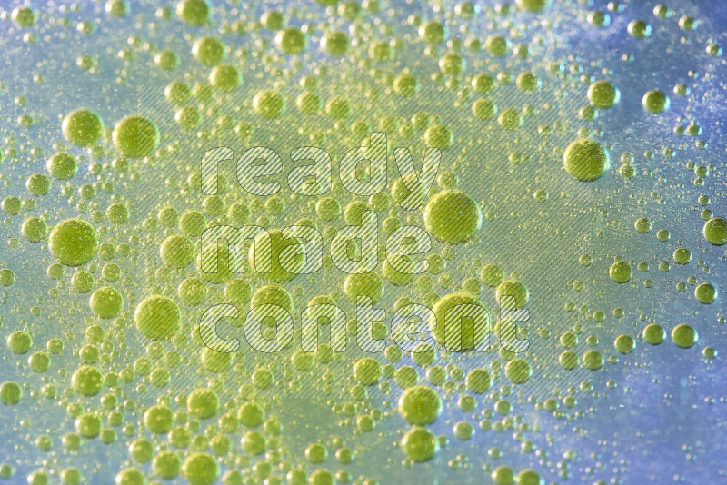 لقطات مقربة لقطرات ألوان مائية صفراء على سطح الزيت على خلفية زرقاء