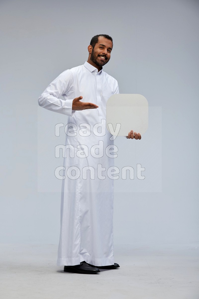 Saudi man wearing Thob standing holding social media sign on Gray background