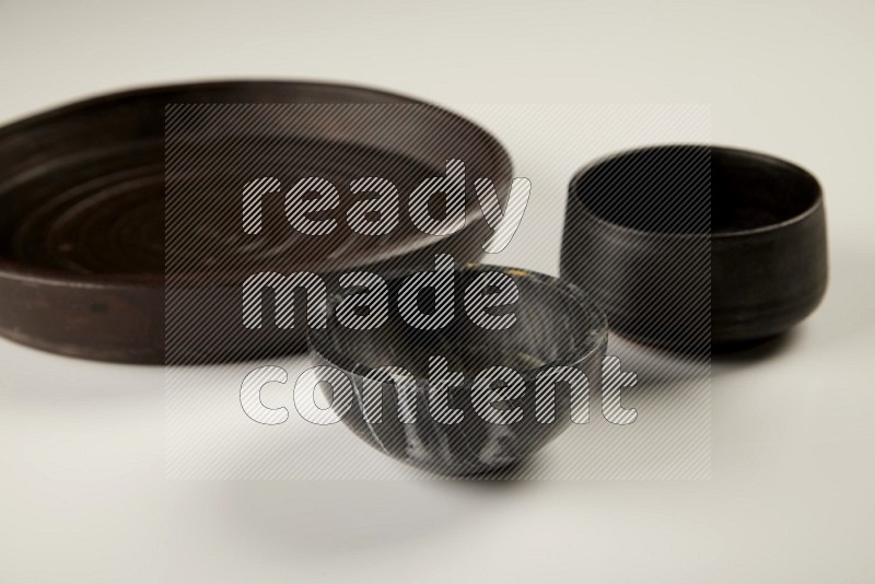 black pottery plate and black bowls on white background