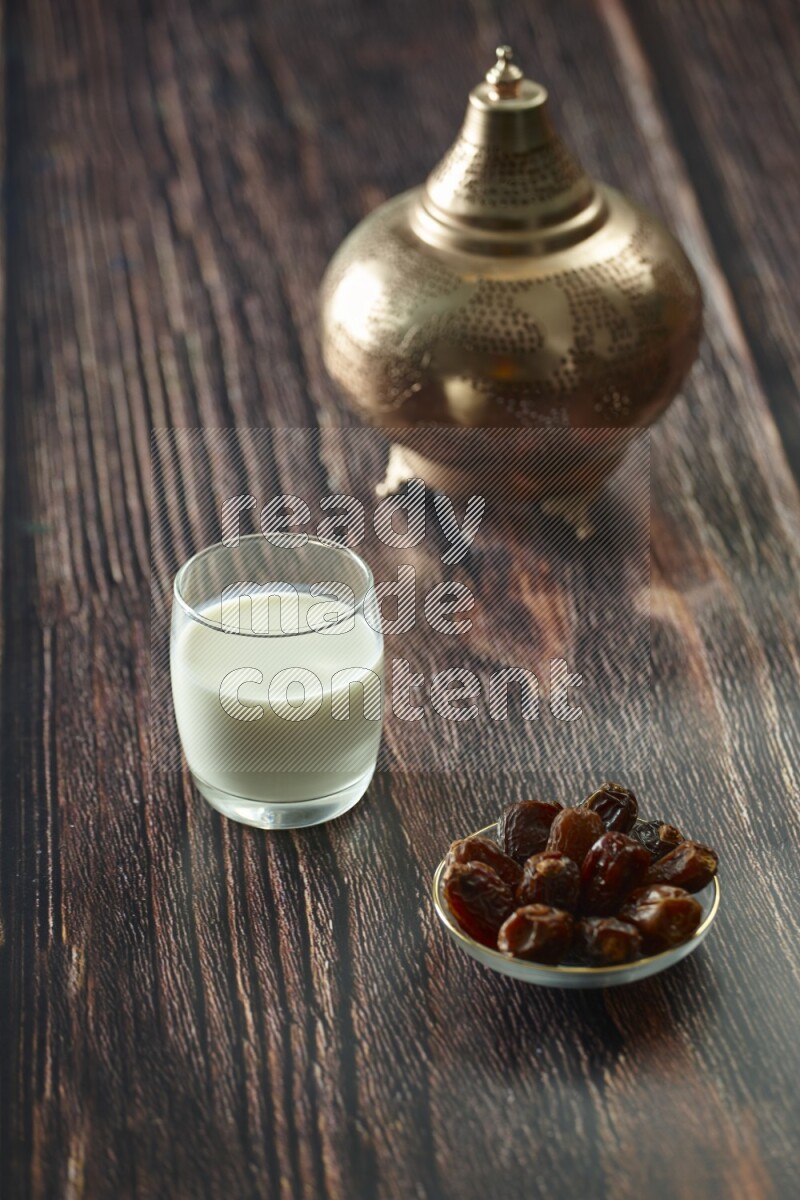 A golden lantern with different drinks, dates, nuts, prayer beads and quran on brown wooden background