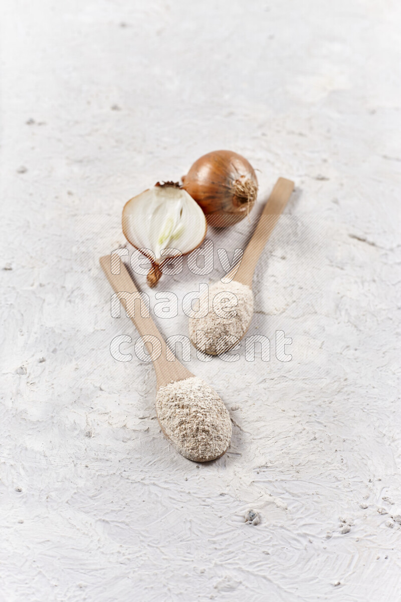 Two wooden spoons full of onion powder on white background