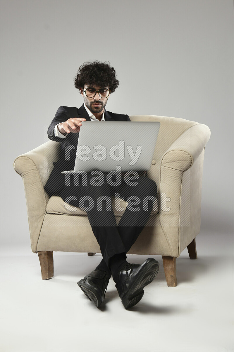 A man wearing formal sitting on a chair working on a laptop on white background