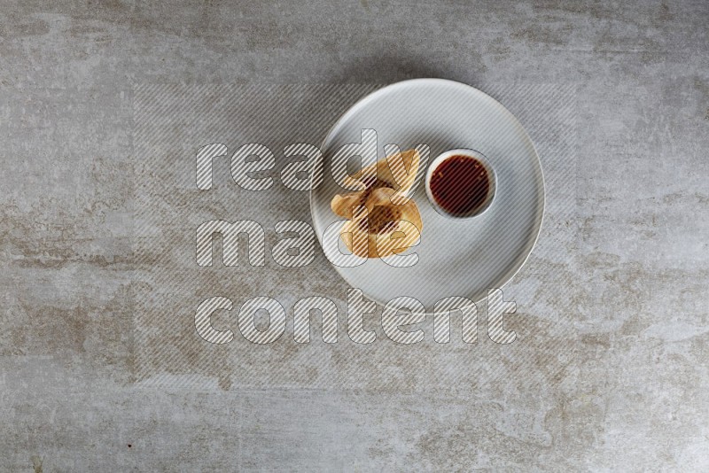 wonton cups with soy sauce ramkin on grey ceramic plate on grey textured counter top