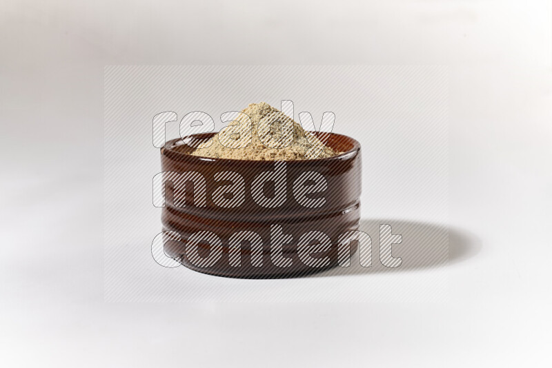 A brown pottery bowl full of ground ginger powder on white background