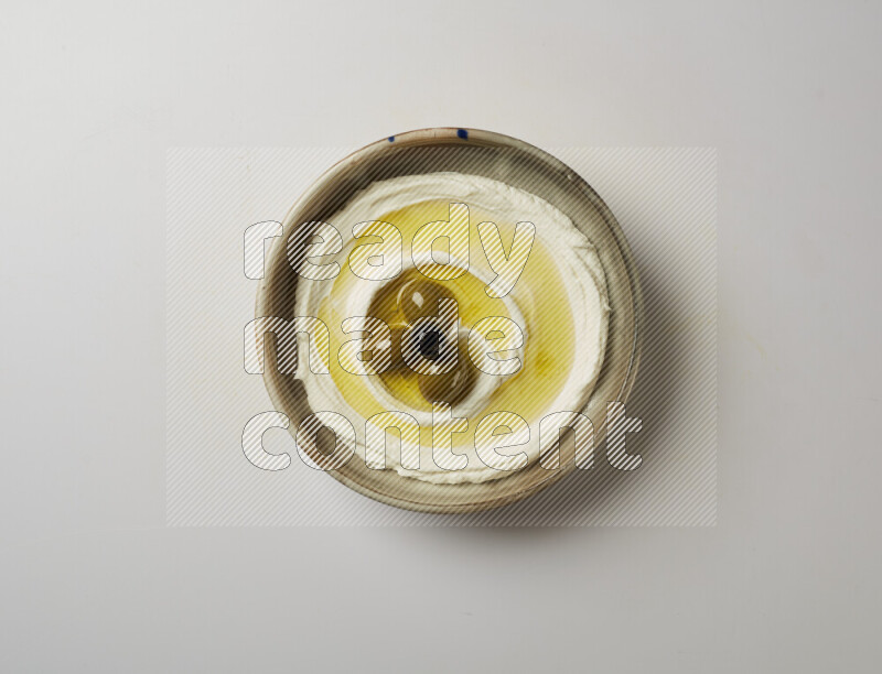 Lebnah garnished with whole olives in a grey pottery plate on a white background