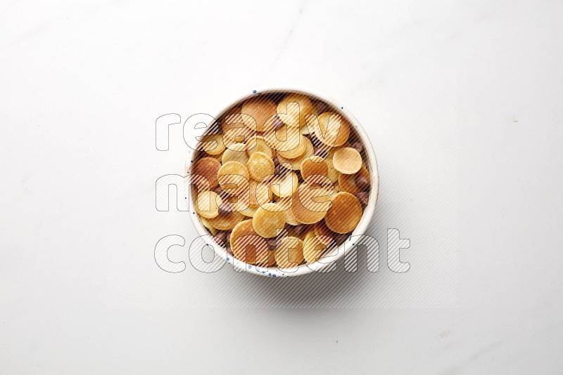 Top-view shot of chocolate chips cereal pancakes in a round bowl on white background