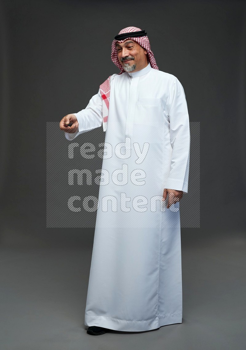 Saudi man with shomag Standing holding car key on gray background