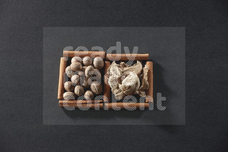 2 squares of cinnamon sticks full of nutmeg and dried ginger on black flooring