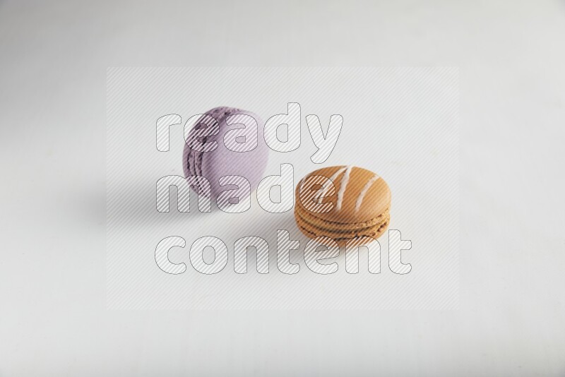 45º Shot of of two assorted Brown Irish Cream, and Purple Blueberry macarons on white background