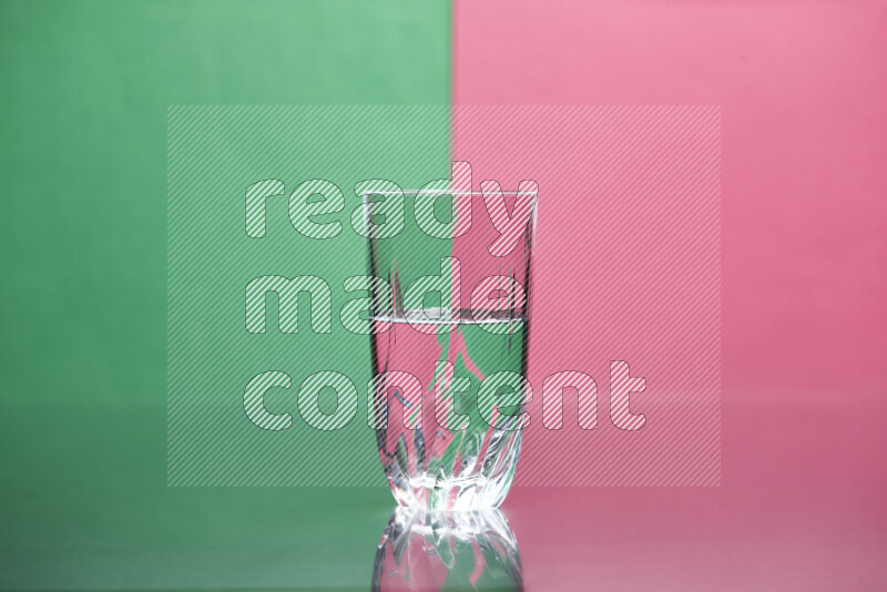 The image features a clear glassware filled with water, set against green and pink background