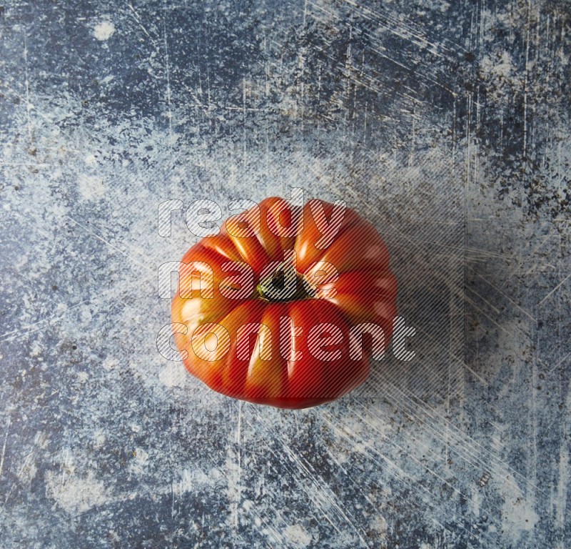 Single Topview Heirloom Tomato on a textured rustic blue background