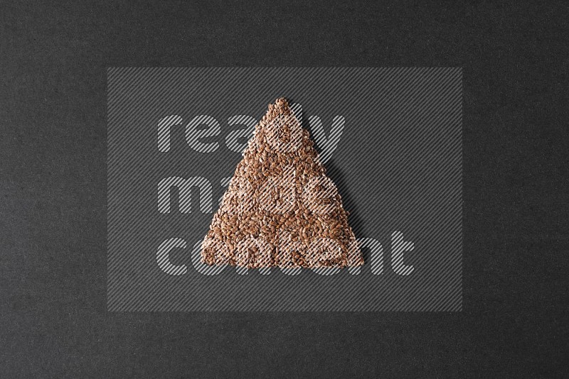 Flax Seeds in a triangle shape on a black Flooring