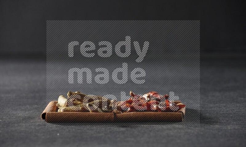 مربعان من أعواد القرفة ممتلئان بالفلفل الحار المجفف وأصابع الكركم علي خلفية سوداء