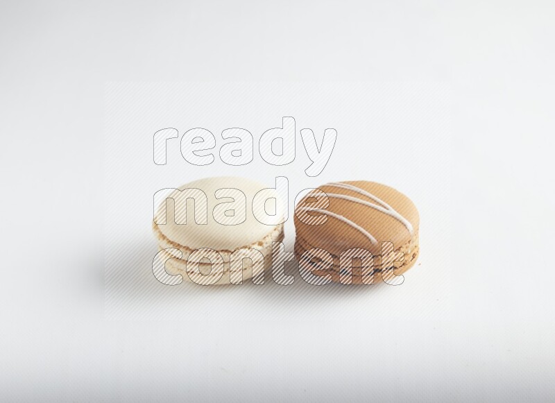 45º Shot of of two assorted Brown Irish Cream, and White Caramel fleur de sel macarons on white background