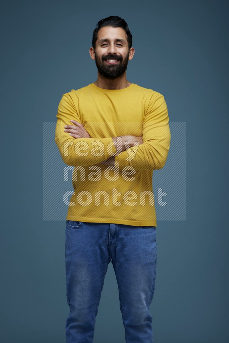Man posing in a blue background wearing a yellow shirt