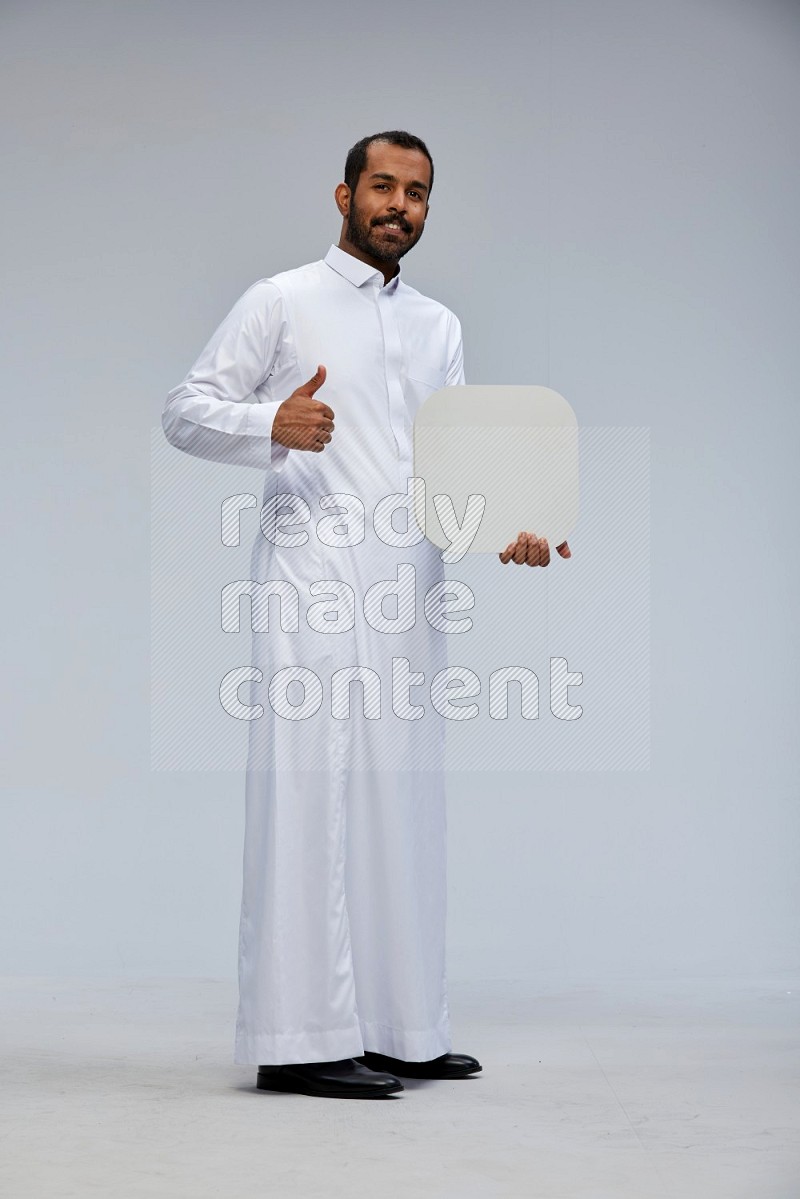 Saudi man wearing Thob standing holding social media sign on Gray background