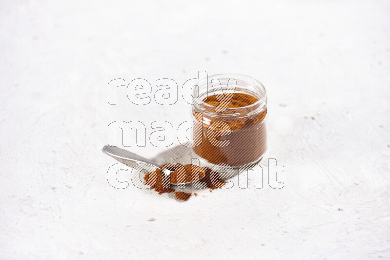 A glass jar full of ground paprika powder on white background