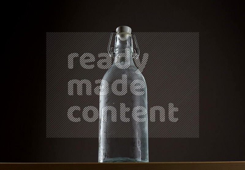 Low angle shot of a bottle of water and ice on grey background