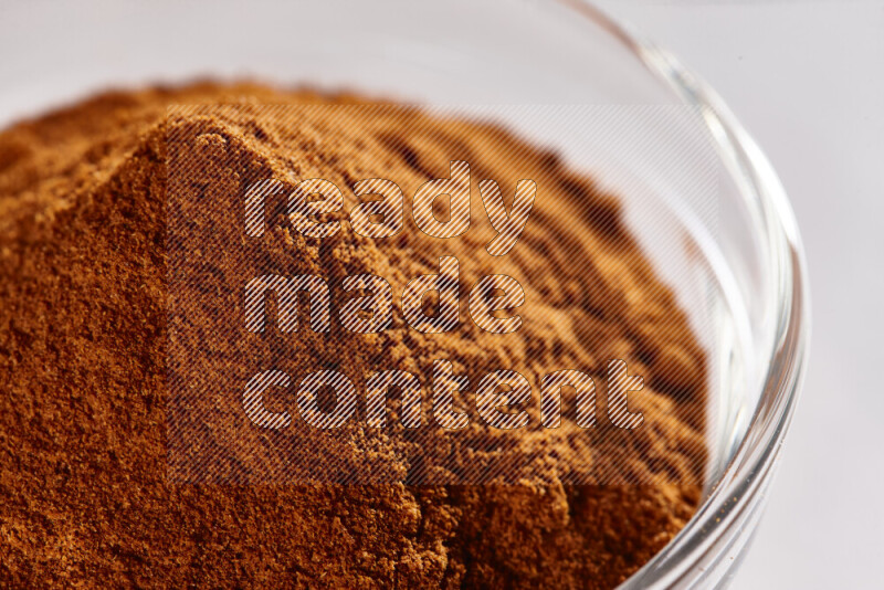 A glass bowl full of ground paprika powder on white background