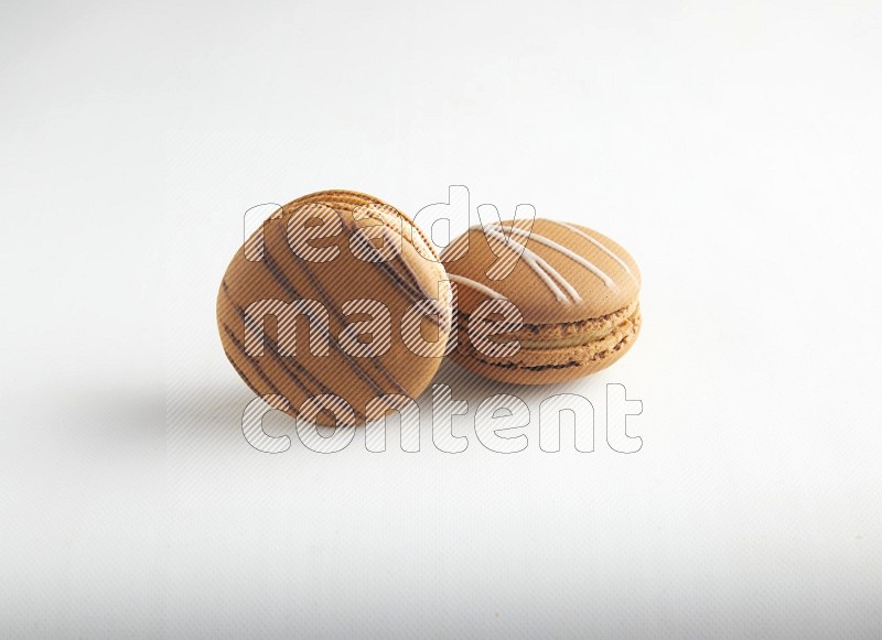 45º Shot of of two assorted Brown Irish Cream, and light brown  Almond Cream macarons on white background