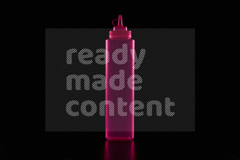 A squeeze bottle with colored rim light against black background