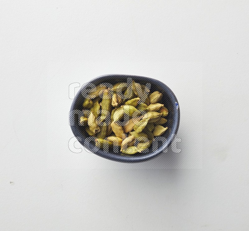 Top-view shot of Cardamon in a container on white background