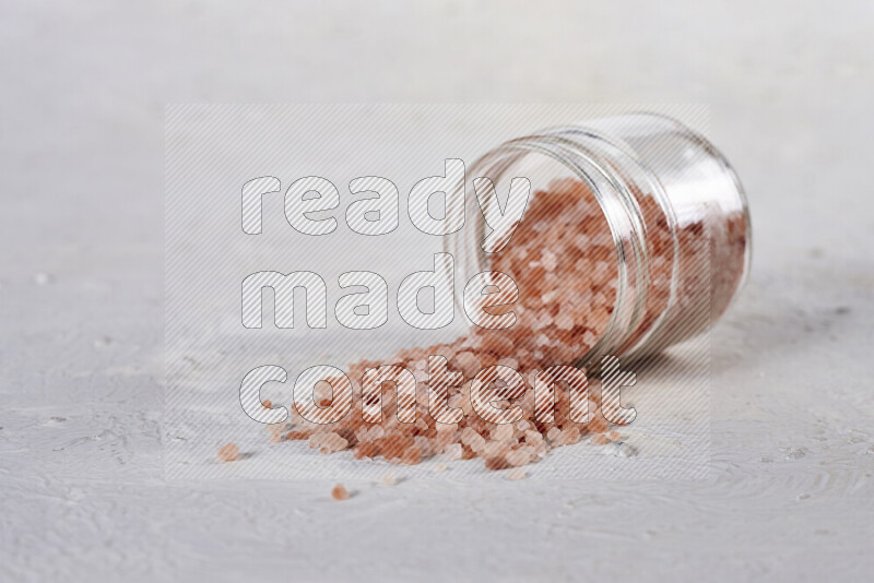 A glass jar full of coarse himalayan salt crystals on white background